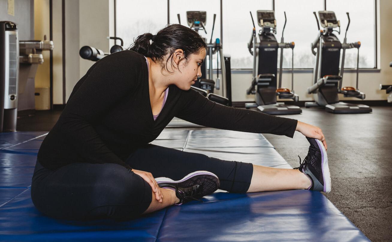 Female student stretching on exercise mat